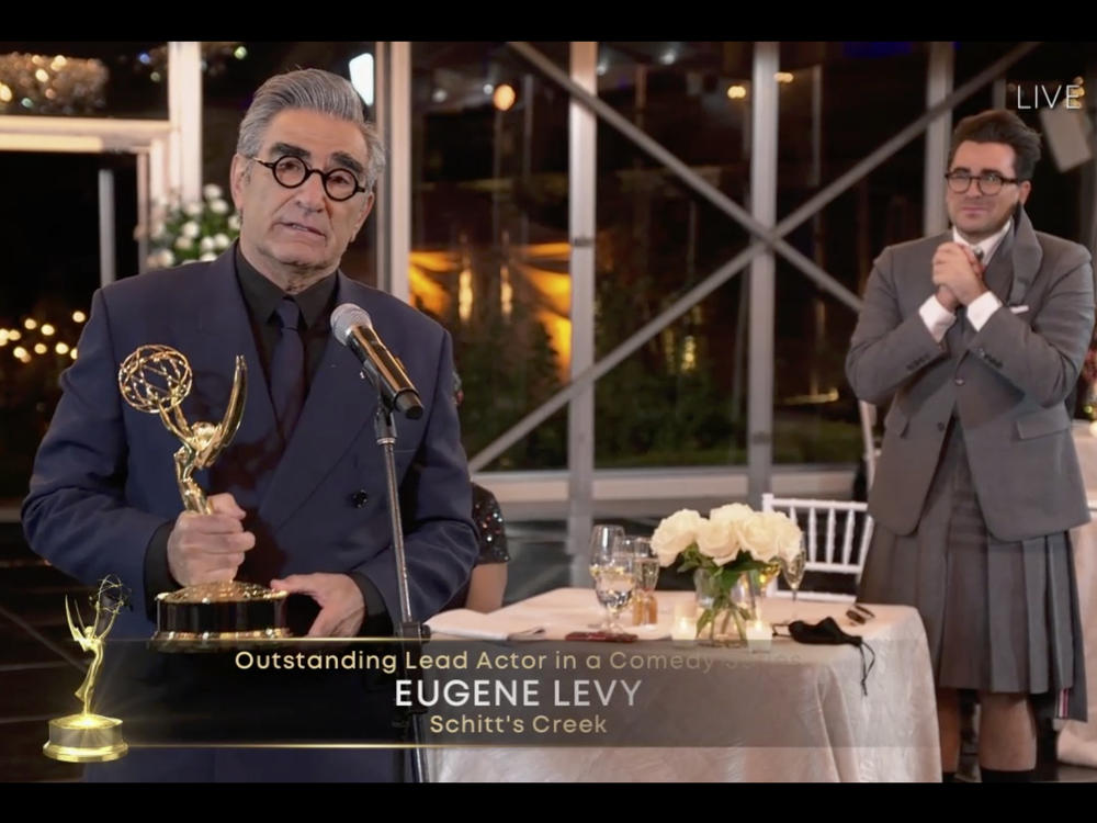Eugene Levy accepts his award for lead actor in a comedy series for <em>Schitt's Creek </em>as his son (and creative partner) Dan Levy looks on at Sunday night's Emmy Awards.