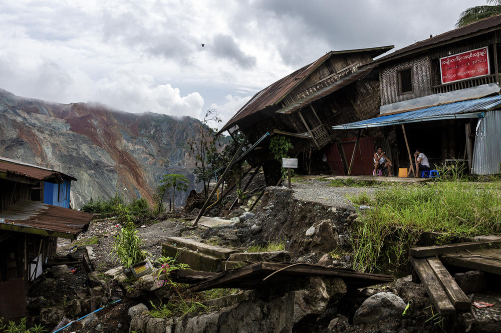Residents sit near a damaged house caused by a landslide at a mining site in Hpakant in July. The landslide killed nearly 200 people.