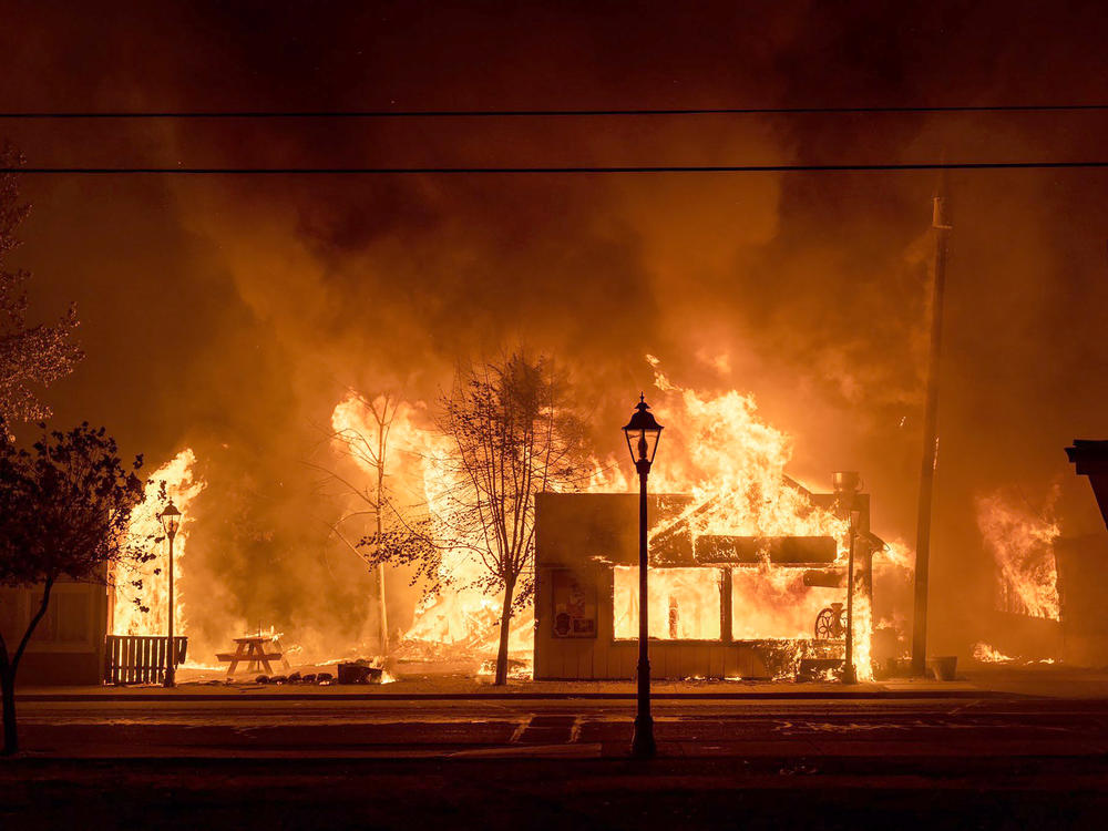 Buildings are engulfed in flames as a wildfire ravages Talent, Ore., on Sept. 8, 2020. Unfounded rumors that left-wing activists were behind the fires went viral on social media, thanks to amplification by conspiracy theorists and the platforms' own design.
