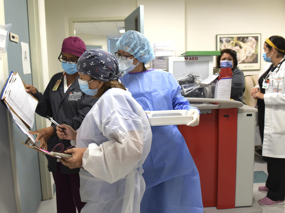 Researchers in Miami hold syringes containing either a placebo or the candidate COVID-19 vaccine from Moderna. Their work is part of a phase three clinical trial sponsored by the National Institutes of Health.