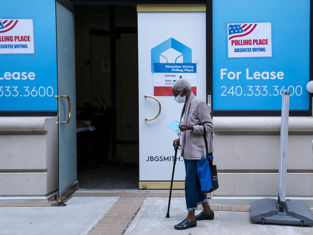 A voter wearing a protective mask exits from an early voting location in Arlington, Va.