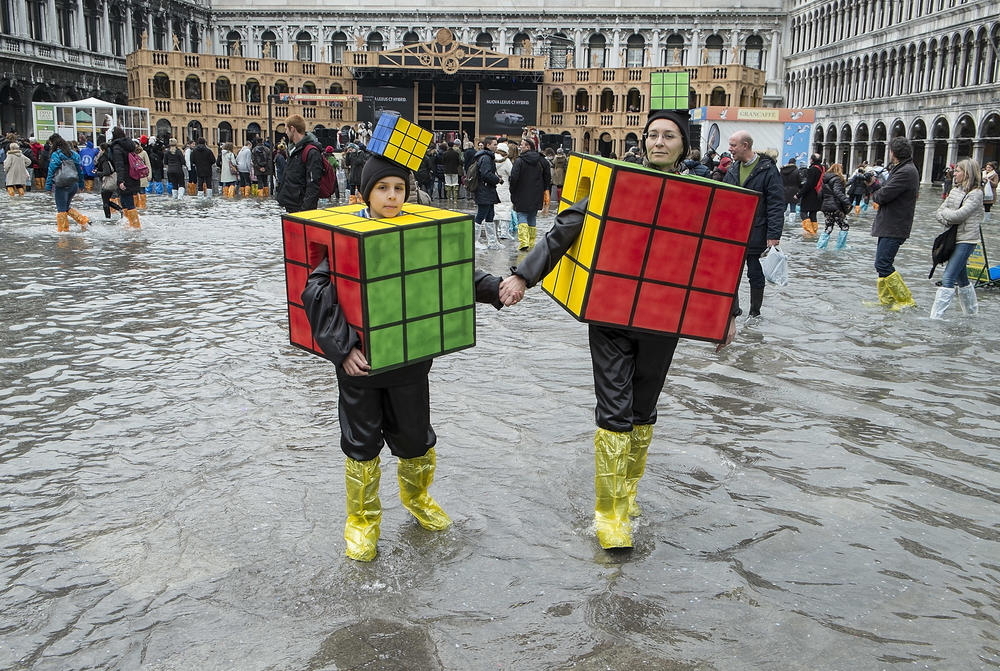 A mother and son wearing Rubik's Cube costumes walk in flooded Saint Mark's Square on the last day of Carnival on March 4, 2014, in Venice, Italy.