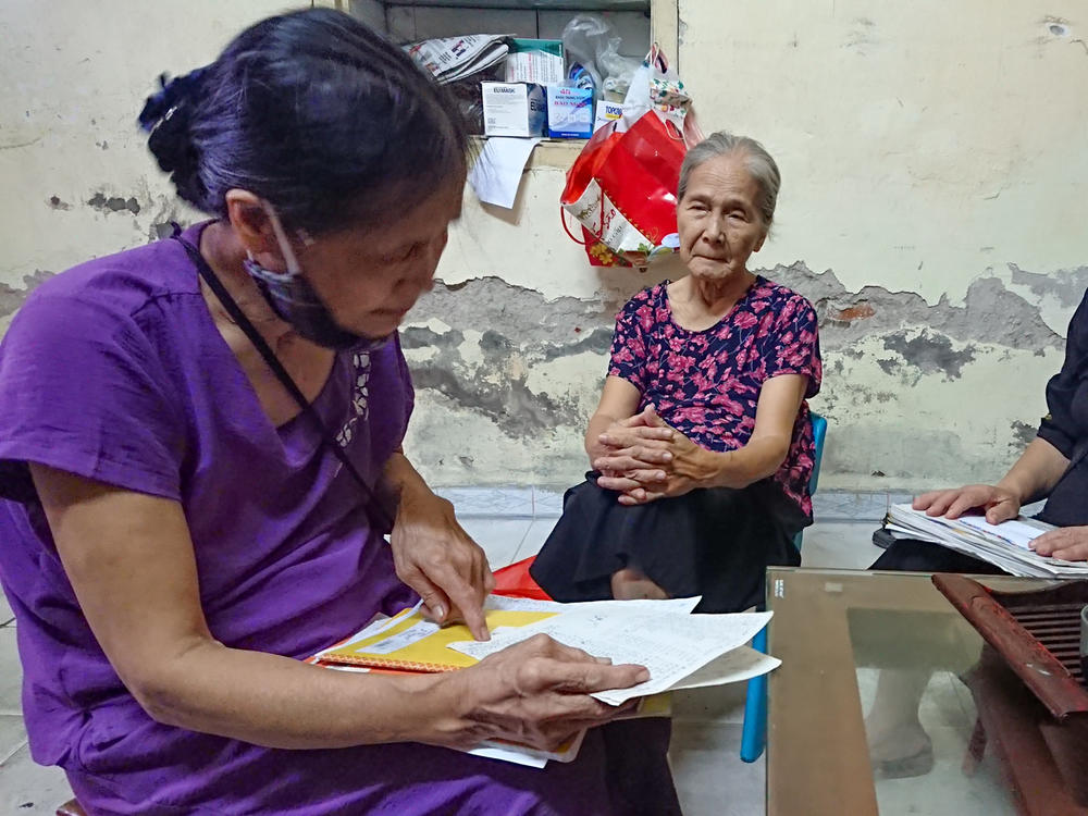 Dao Thi Hoa, right, chairwoman of the Intergenerational Self Help Club in the Khuong Din ward of Hanoi in Vietnam, checks the club's account book with other members.