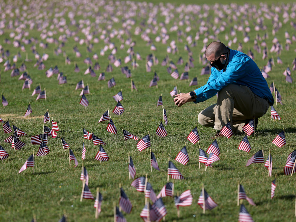 The U.S. hit a tragic milestone Tuesday, recording more than 200,000 coronavirus deaths. Here, Chris Duncan, whose 75-year-old mother, Constance, died from COVID-19 on her birthday, visits a COVID Memorial Project installation of 20,000 U.S. flags on the National Mall. The flags are on the grounds of the Washington Monument, facing the White House.