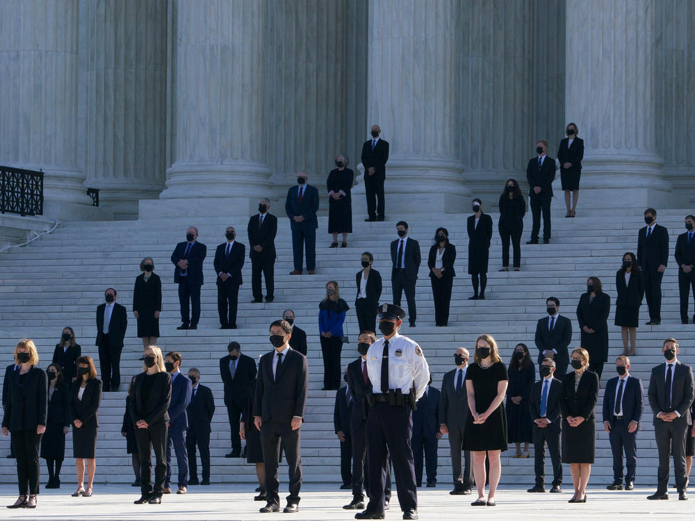 Former law clerks for Justice Ruth Bader Ginsburg stand on the steps of the U.S. Supreme Court in Washington, D.C., as they await the arrival of the casket on Wednesday.