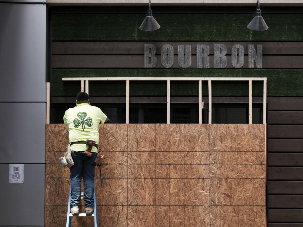 A worker boards up a business in downtown Louisville on Tuesday in anticipation of the results of a grand jury inquiry into the death of Breonna Taylor.
