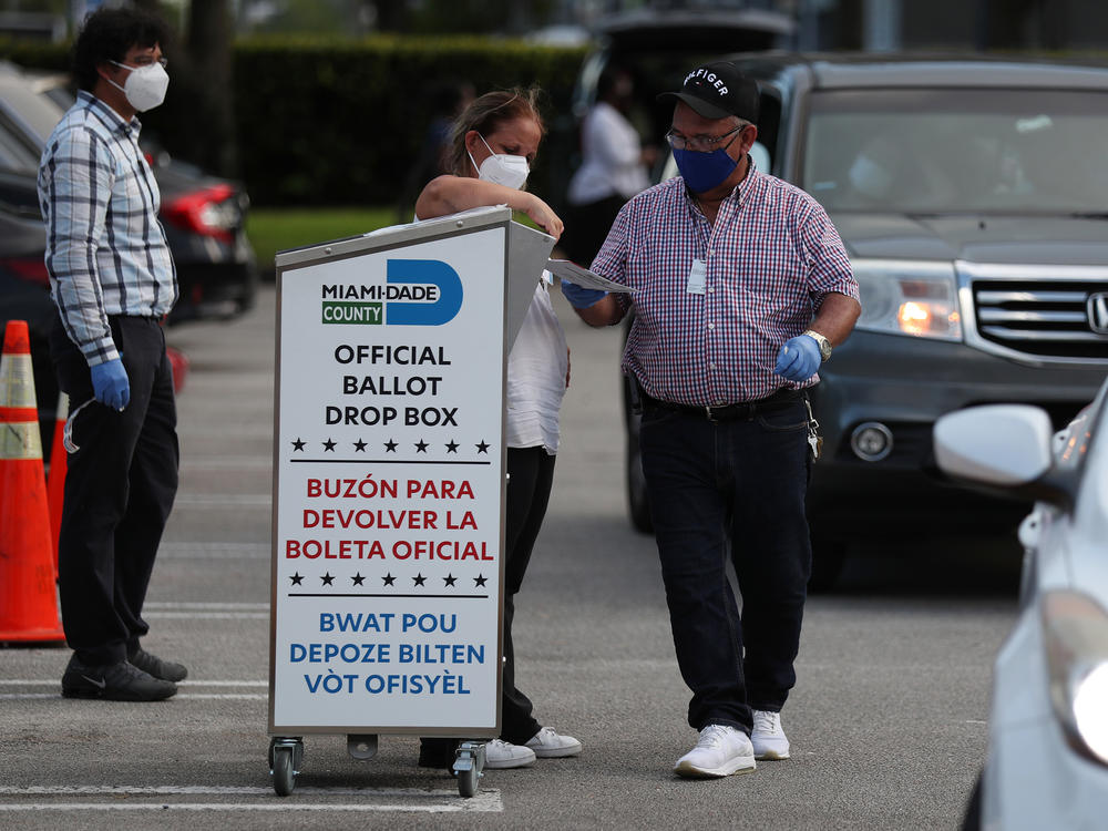 Poll workers at the Miami-Dade County Elections Department deposit returned mail-in ballots into an official ballot drop box on primary election day on Aug. 18 in Doral, Fla.