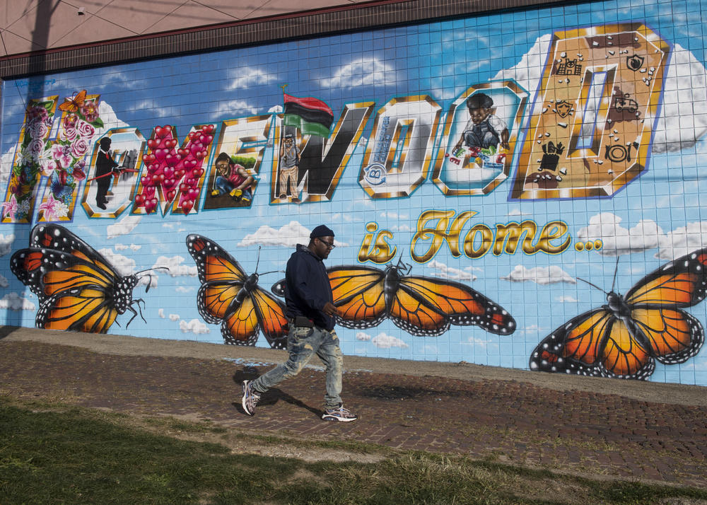William Allen walks by a mural in the Homewood neighborhood of Pittsburgh.