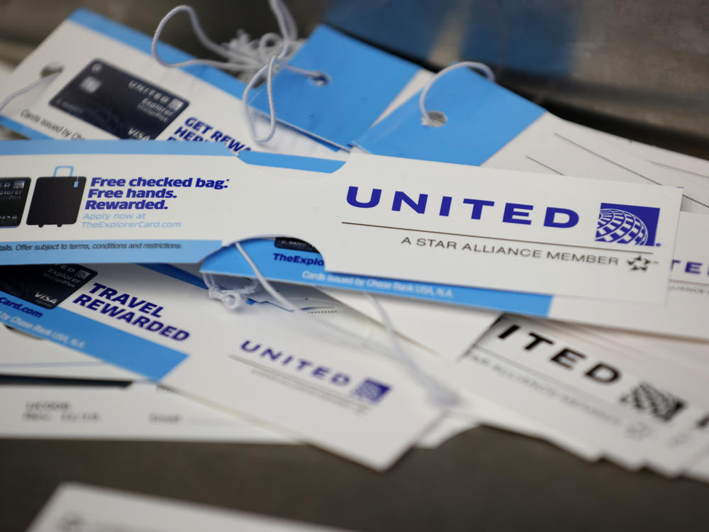 United Airlines baggage tags are displayed on a table at San Francisco International Airport. The carrier says it's starting a pilot program next month that will offer rapid coronavirus testing at the airport or via a self-collected, mail-in test ahead of a flight.