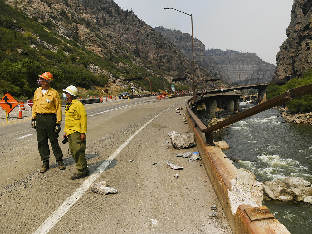 Great Basin National Incident Management One Team Public Information Officers Wayne Patterson, left, and Mike Ferris, center, check out rock fall that fell from high cliffs causing damage onto I-70 below making it dangerous for passing vehicles during the Grizzly Creek Fire in Glenwood Canyon on August 17, 2020 near Glenwood Springs, Colorado.
