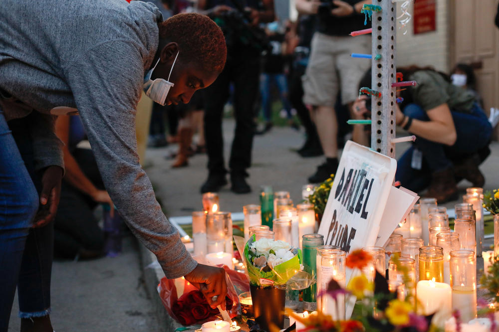 A demonstrator lights a candle in front of a memorial on Sept. 3, while taking part in a protest against police over the death of Daniel Prude in Rochester, New York.