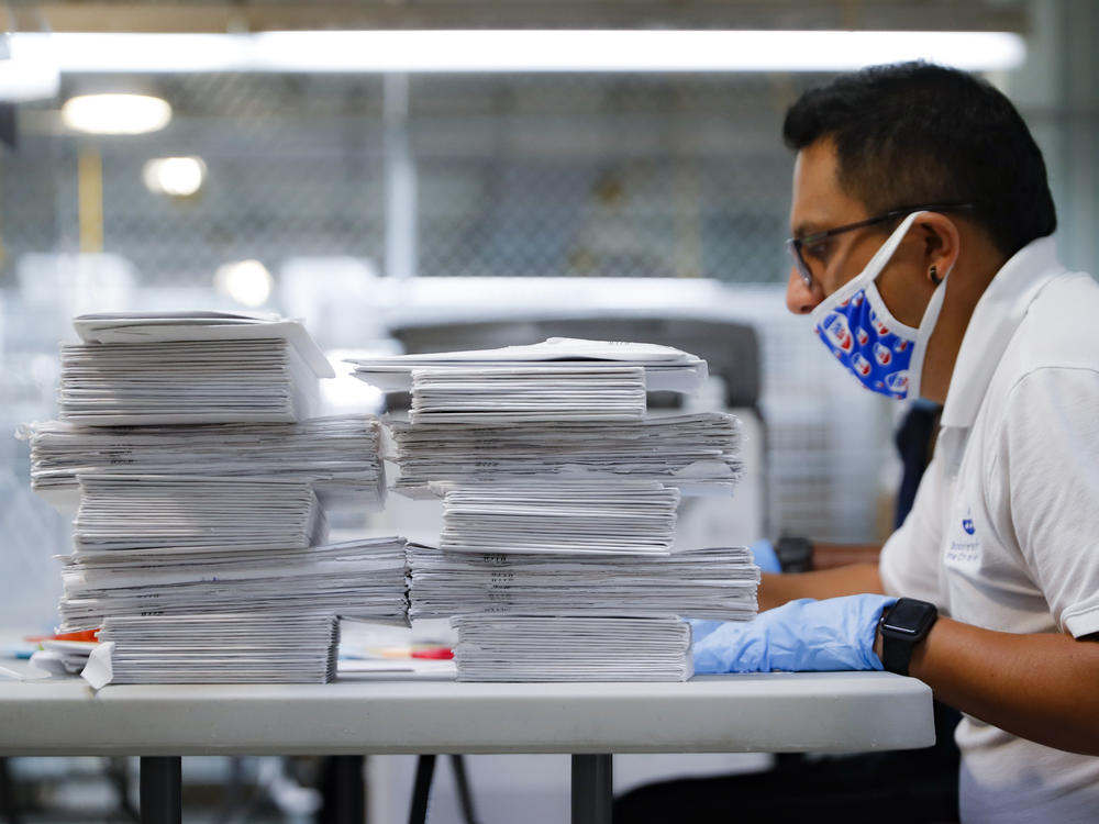 A worker prepares to check stacks of ballots in July at a Board of Elections facility in New York City. The city's election board says it will send about 100,000 new absentee ballots to voters after mailing out error-filled ones.