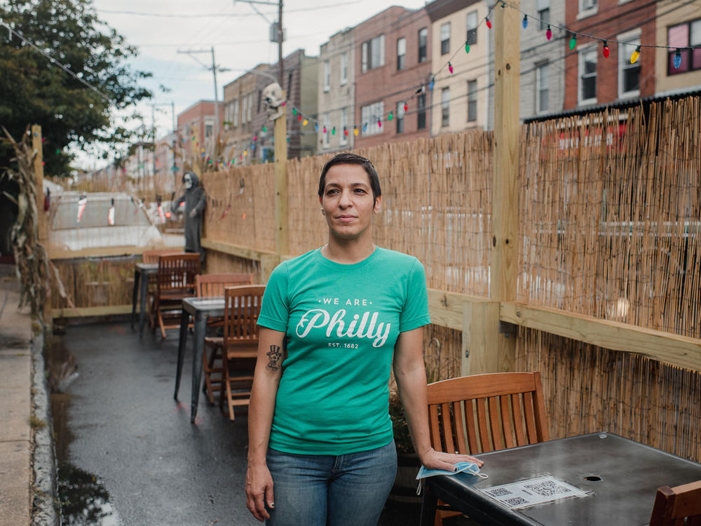 Danielle Renzulli, owner of 12 Steps Down Bar in Philadelphia, poses by the tables she has set up in what used to be parking spots. She was expecting some negative reactions from neighbors, given how valuable parking is in the area, but to her surprise, she received no complaints.