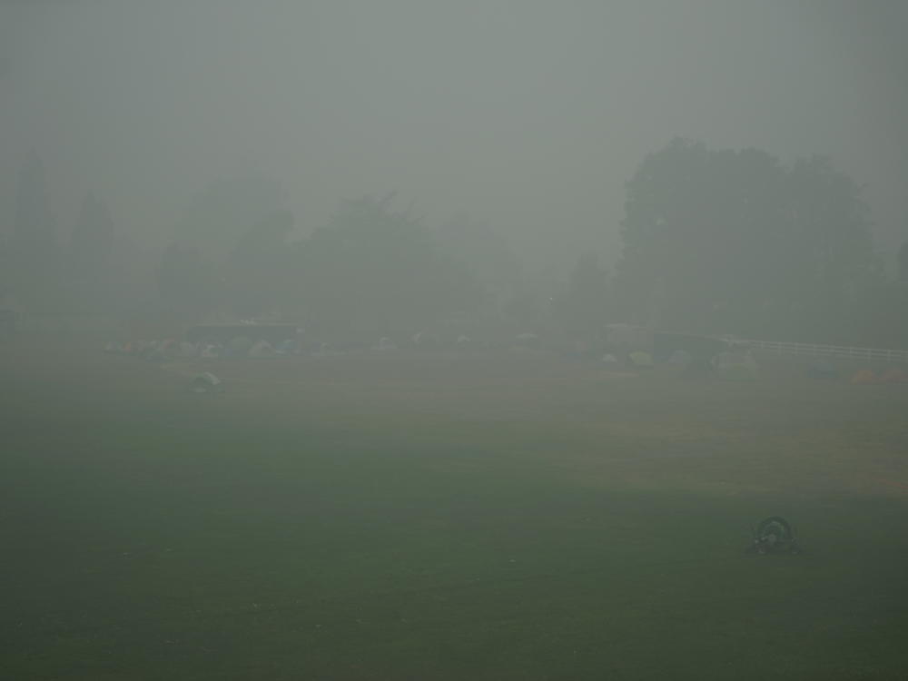Tents of a fire camp, where firefighters sleep between shifts, is shrouded in thick smoke. On large incidents with remote field camps, many wildland firefighters get no break from smoke.