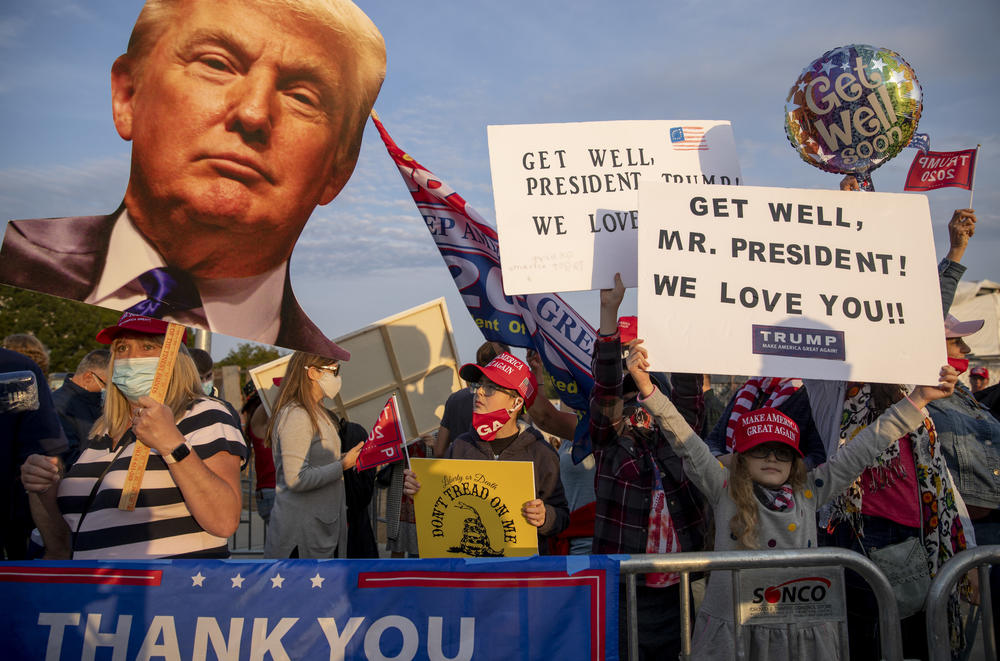 On left, Darla Cable of Cabin John, Md., holds a Trump cutout as others show their signs.