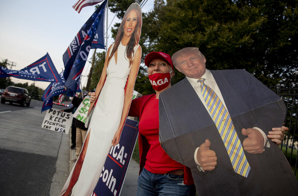 Tatiana Demidio of Arlington, Va., but originally from Moscow holds cutout posters of the president and First Lady as they cheer and cars blow their horns.