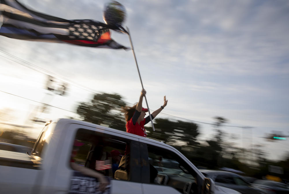 A Trump supporter holds U.S. flag as she rides down the road in front of Walter Reed Medical Center.