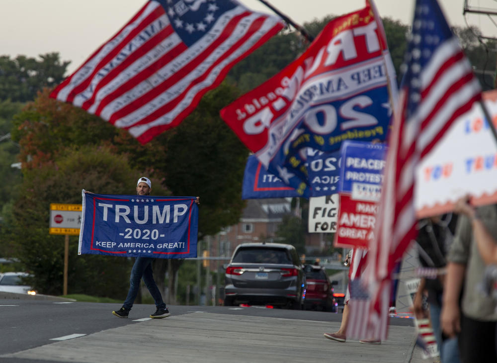 A Trump supporter carries his flag into the street just outside of Walter Reed Medical Center.