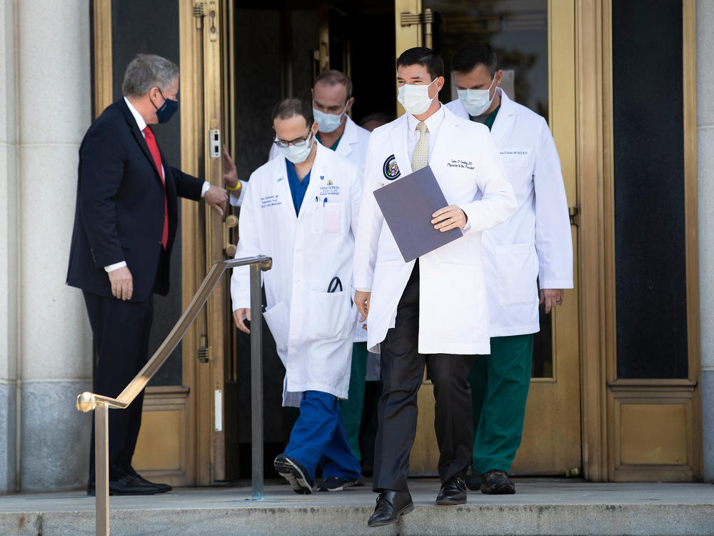 White House chief of staff Mark Meadows holds the door for White House physician Dr. Sean Conley (center) and other members of the president's medical team ahead of a briefing for reporters on Sunday.