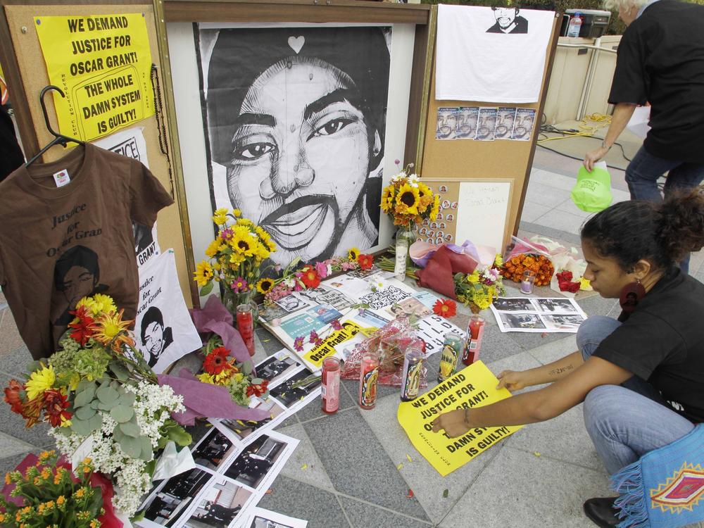A woman leaves a sign at a street-side memorial to shooting victim Oscar Grant in Oakland, Calif., in 2010. A Northern California prosecutor announced Monday that she will reopen the investigation into the killing of Grant at a train station by a police officer 11 years ago.