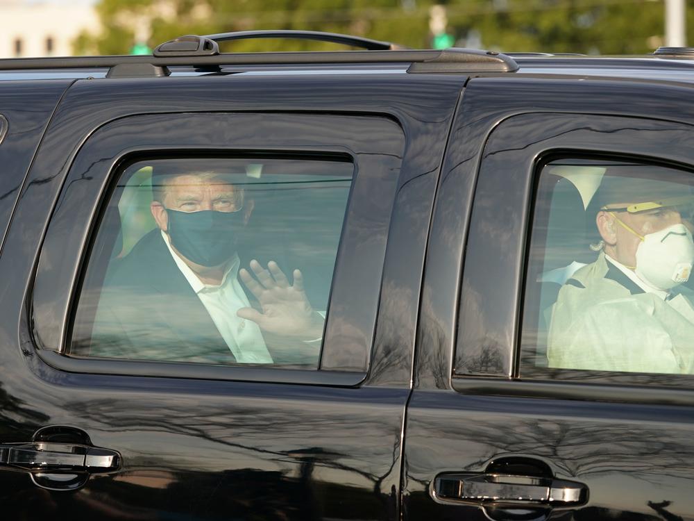 President Trump waves from a motorcade outside Walter Reed Medical Center, accompanied by Secret Service agents on Sunday.