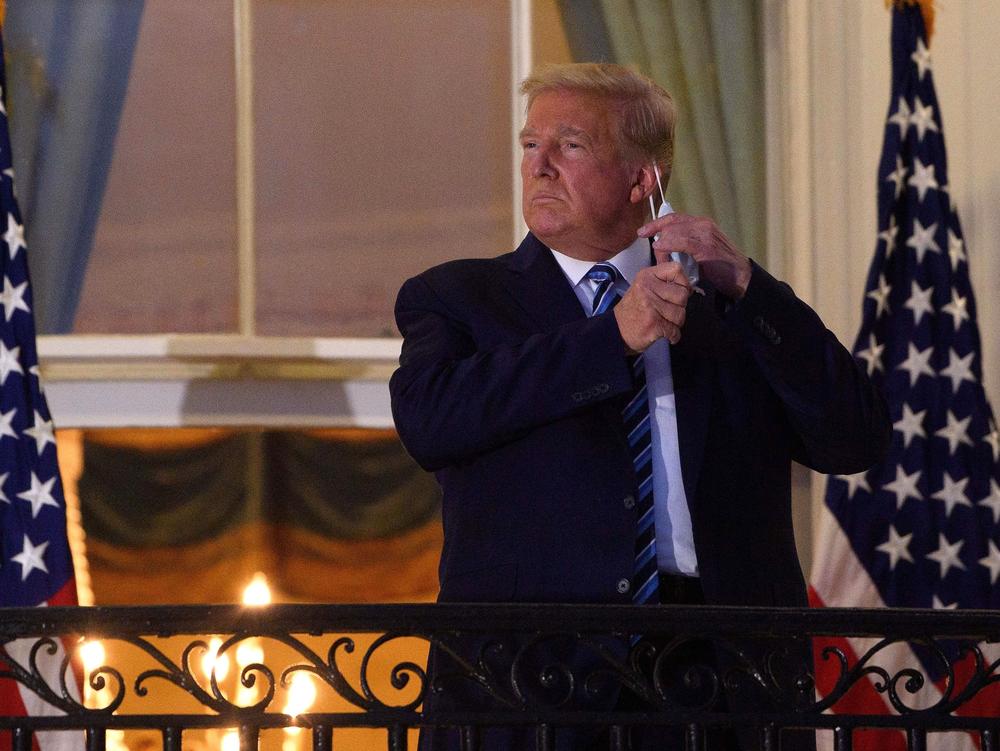 President Trump takes off his face mask Monday night as he arrives at the White House upon his return from Walter Reed National Military Medical Center.