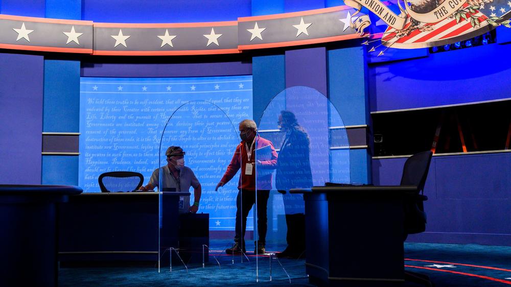 Workers install plexiglass protections on the stage of the debate hall ahead of the vice presidential debate Salt Lake City.