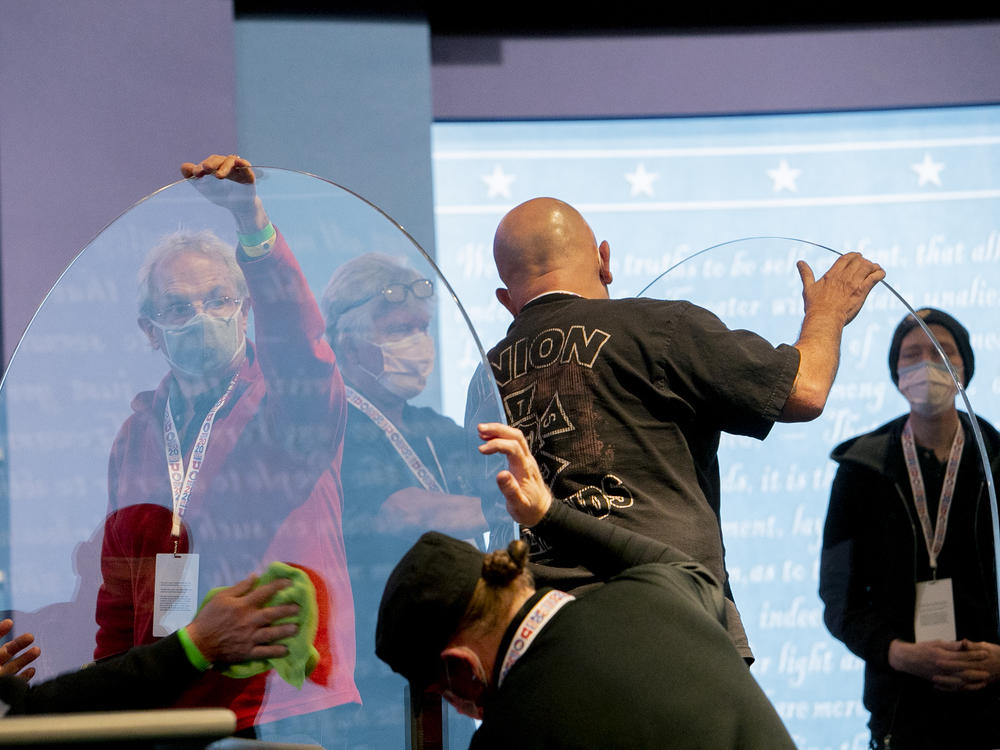 Workers clean plexiglass dividers installed at the University of Utah in preparation for the debate between Sen. Kamala Harris and Vice President Pence.