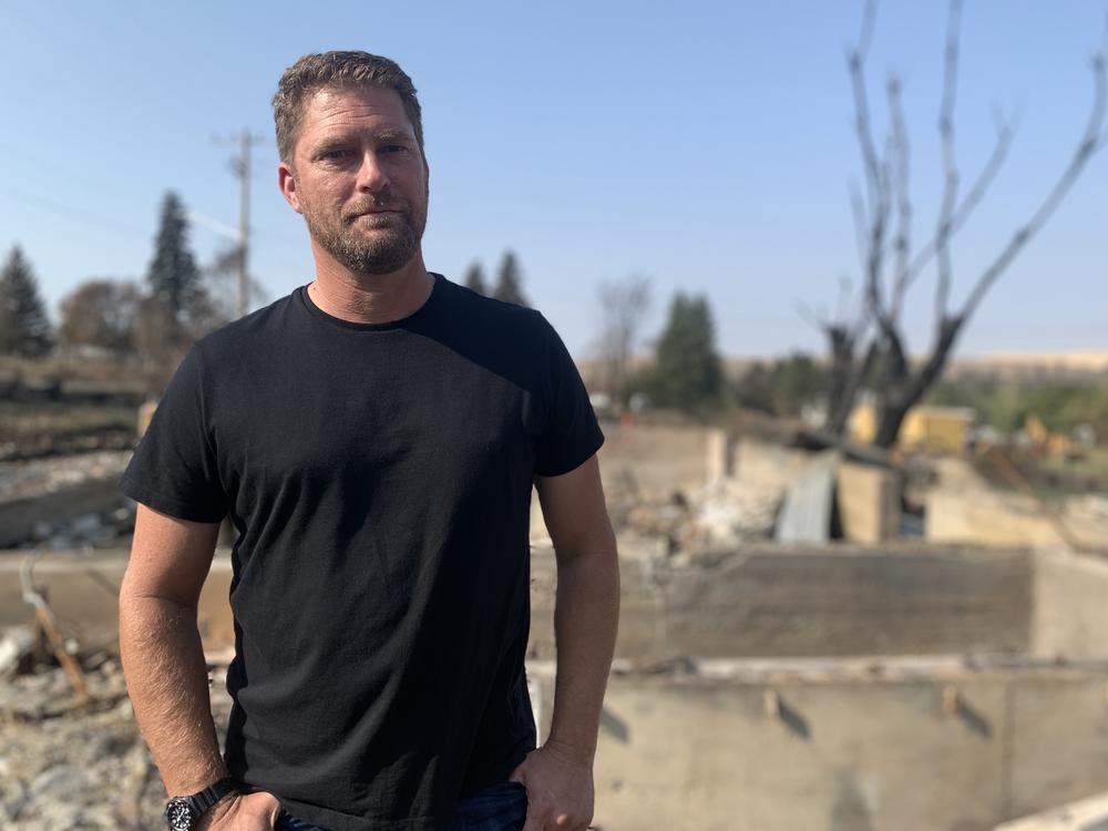 Scott Hokonson, a town council member and volunteer firefighter, stands in the rubble of his home, which was destroyed by the wildfire.