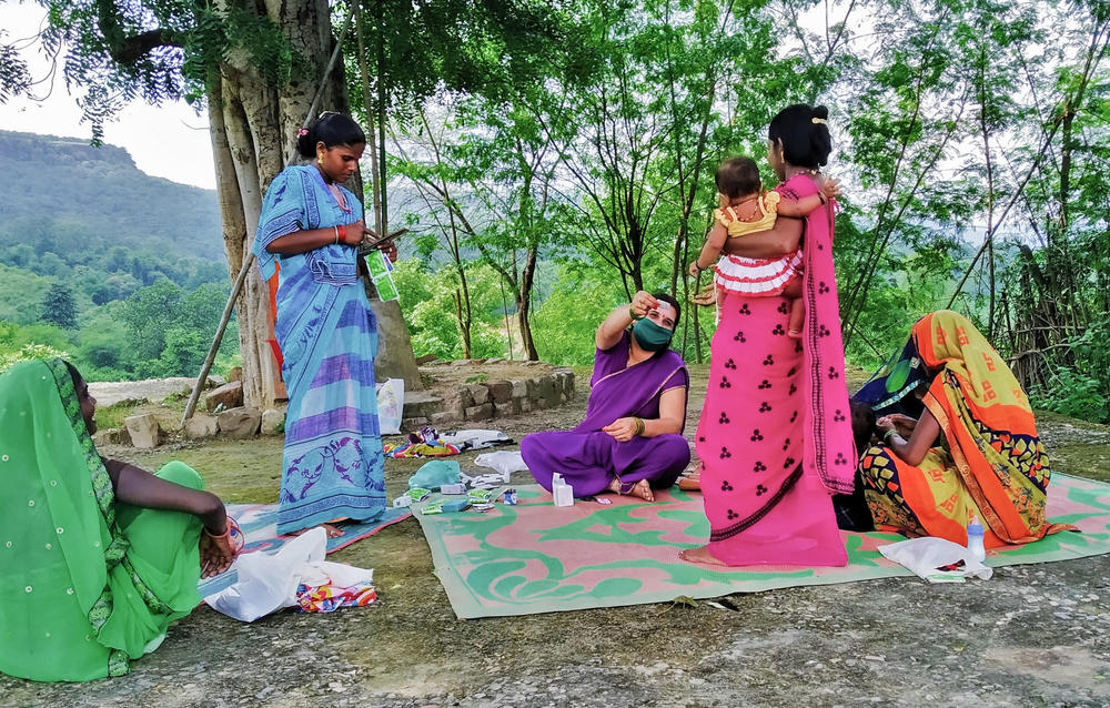 Dwivedi, in purple sari, shares health information with women in the village. COVID-19 is a hot topic.