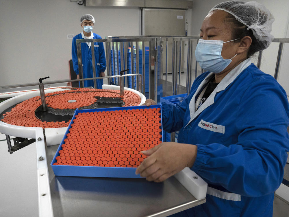 A worker feeds vials for production of a vaccine for COVID-19 at the SinoVac vaccine factory in Beijing. China said on Friday that it is joining the COVID-19 vaccine alliance known as COVAX.