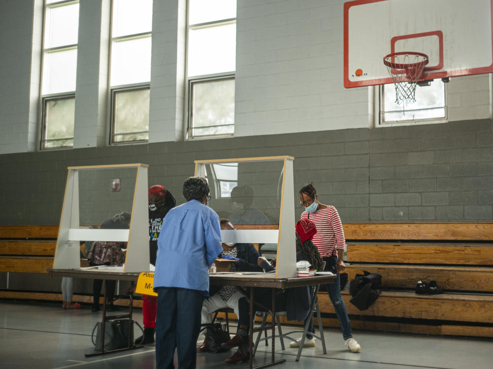 Poll workers sit behind plexiglass barriers during primary elections on June 2 in Philadelphia. Many cities are reporting a surge of volunteers to work the polls although Philadelphia still faces a shortage ahead of next month's election.