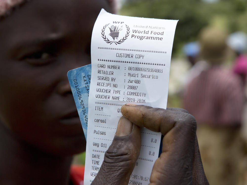 A woman holds a voucher before receiving food aid in Mudzi, Zimbabwe, in February. On Friday, the United Nations World Food Programme received the 2020 Nobel Peace Prize.