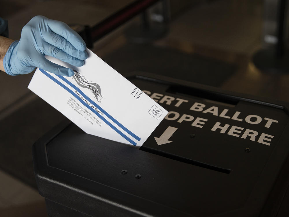 In this May 2020 photo, a voter casts her mail-in ballot at in a drop box in West Chester, Pa., prior to the primary election. On Saturday a federal judge blocked a Trump campaign lawsuit to limit the use of drop boxes in the state.
