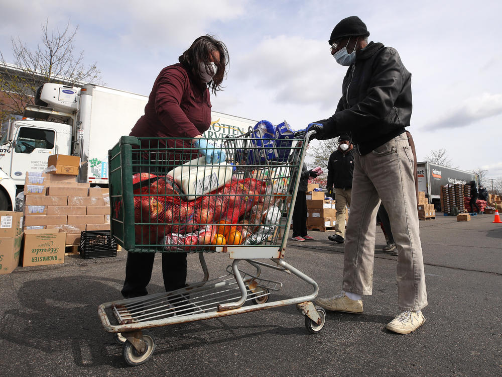 A volunteer loads food into a cart at a mobile pantry in Detroit in April 2020. The COVID-19 pandemic has led to an uptick in the demand at food banks.