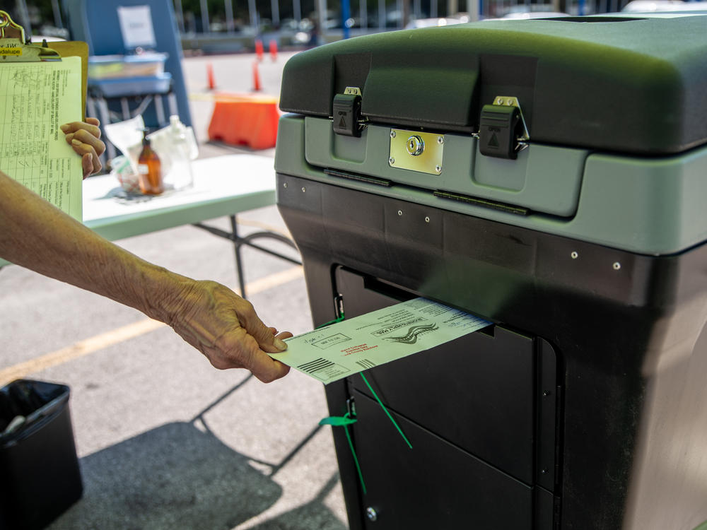 A federal appeals court is allowing Texas Gov. Greg Abbott's limit of one absentee ballot drop-off spot per county to stand, saying voters have many options. Here, a worker puts a ballot into a lockbox at a drive-through mail ballot hand delivery center in Austin.