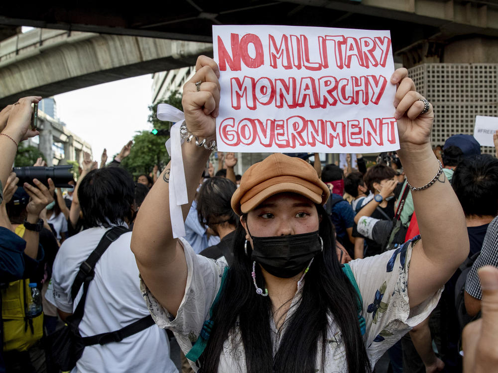 A pro-democracy protester displays a sign during a demonstration Thursday in the central business district of Bangkok.