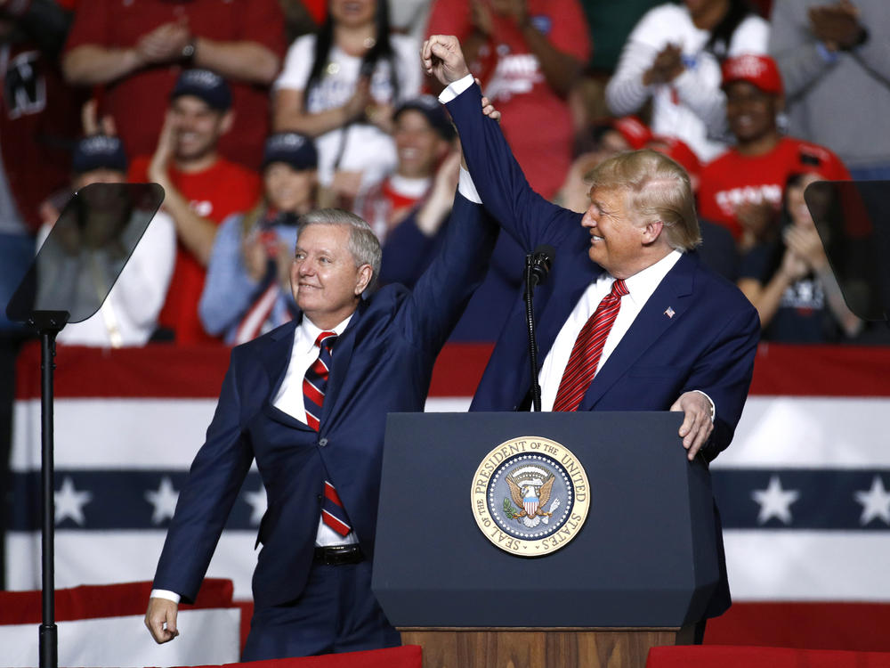 Sen. Lindsey Graham, R-S.C., stands onstage with President Trump during a Feb. 28 campaign rally in North Charleston, S.C. His allegiance to Trump has left some moderate voters feeling snubbed and switching allegiances to Democrat Jaime Harrison.