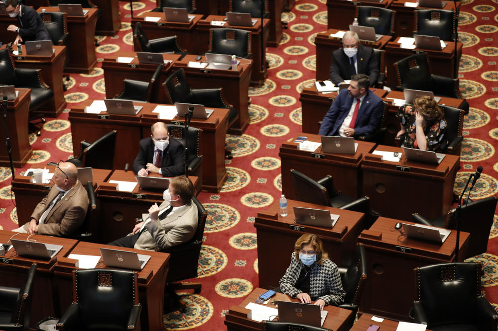 Lawmakers, many wearing masks, sit at their desks inside the House chamber Monday, April 27, 2020, in Jefferson City, Mo.