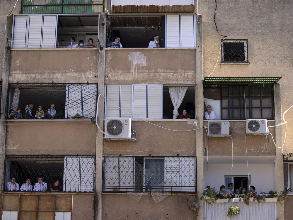 Ultra-Orthodox Jews watch a funeral for Rabbi Mordechai Leifer from their balconies in the port city of Ashdod, Israel, on Oct. 5. The rabbi, who had been the spiritual leader of a small ultra-Orthodox community founded a century ago in Pittsburgh, died after being infected with COVID-19.