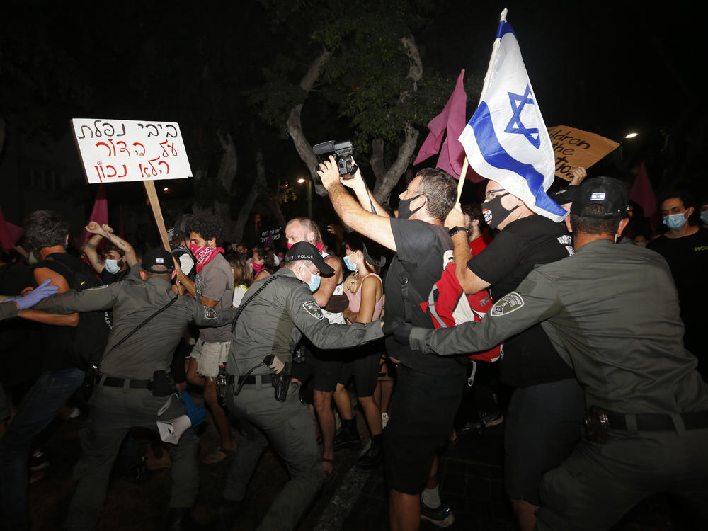 Israeli police scuffle with protesters during a demonstration against Prime Minister Benjamin Netanyahu in Tel Aviv on Oct. 6. Protests continued despite a government ban on large public gatherings, including protests against Netanyahu. The sign reads: 