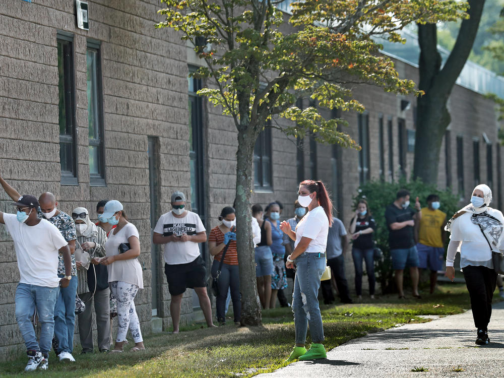 People wait in the shade while in line to get coronavirus tests in Revere, Mass.