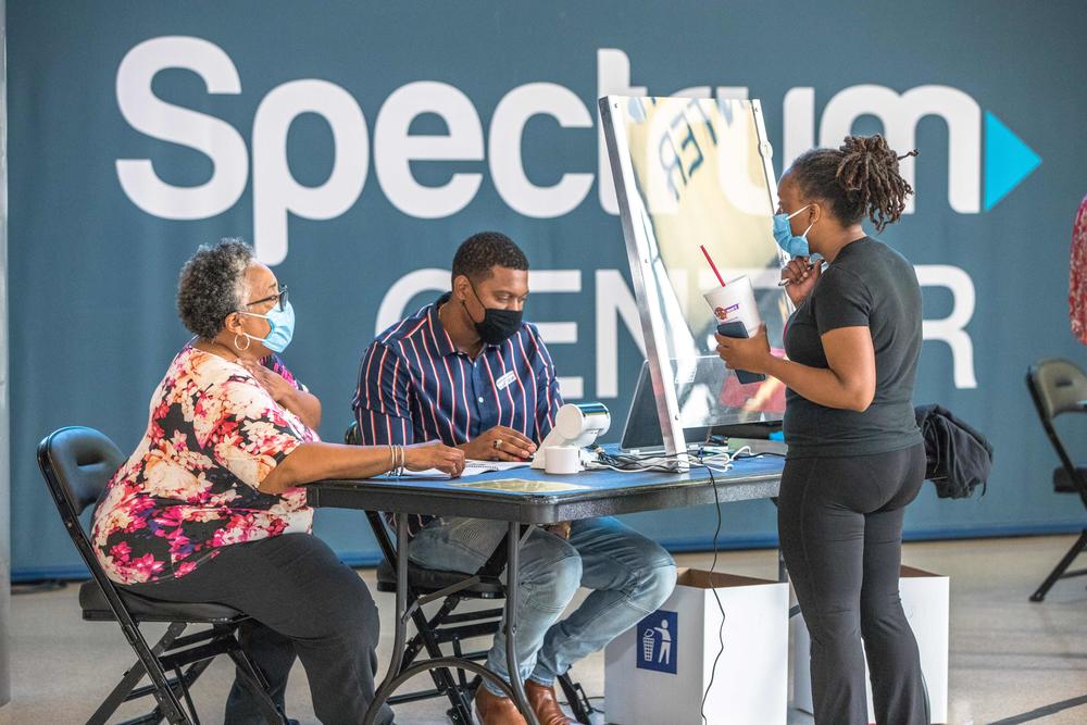 Poll workers assist a voter at the Spectrum Center in Charlotte, N.C., during the first day of early voting there on Thursday.