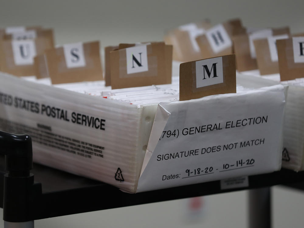 Mail-in ballots that need to be reviewed because of signature discrepancies sit in boxes at the Miami-Dade County Elections Department in Doral, Fla., on Oct. 15. Signature problems are a frequent reason that ballots are rejected, though many states allow voters to fix those problems before Election Day.