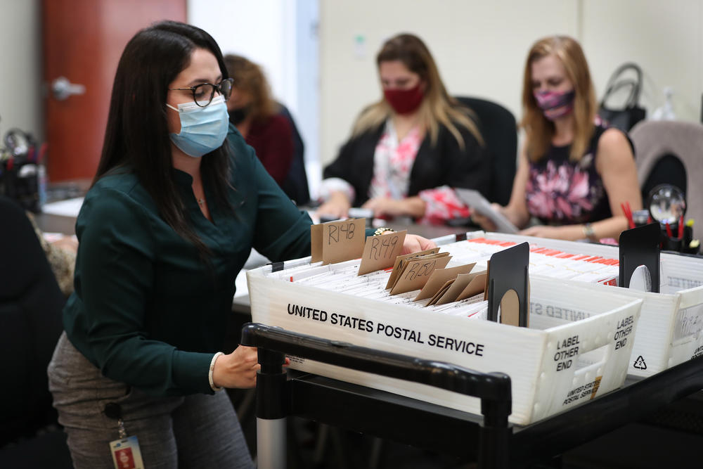 An election worker sorts a box of mail ballots in Doral, Fla., on Oct. 15.