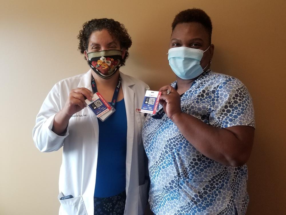 Dr. Madelaine Tully, left, and medical assistant Marshae Love hold up their VotER badges at Progressive Community Health Center in Milwaukee. VotER is an initiative to register new voters at ERs and clinics.