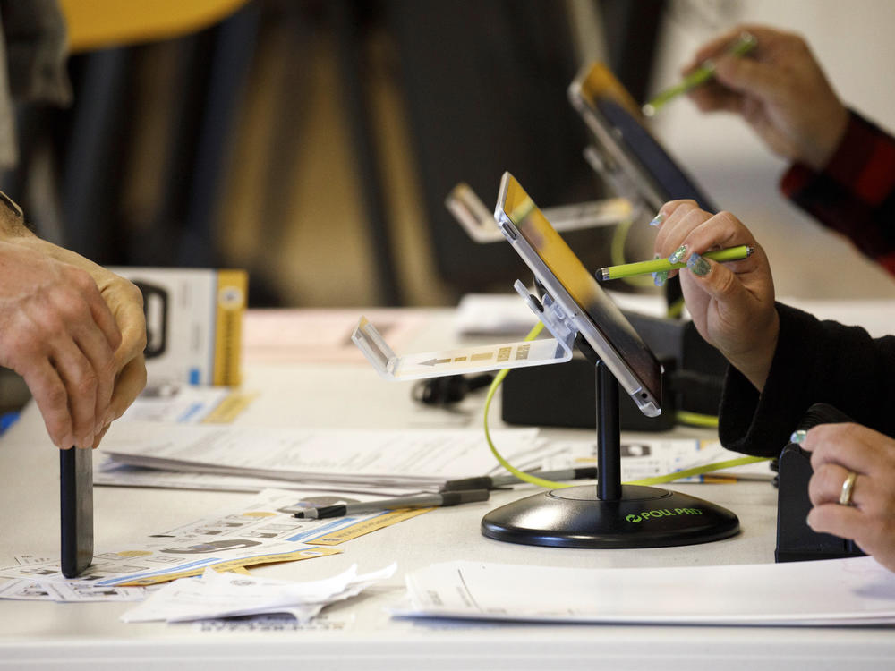 An election worker uses an electronic pollbook to check voters at a polling station in the Echo Park Recreation Complex in Los Angeles on March 3, 2020.