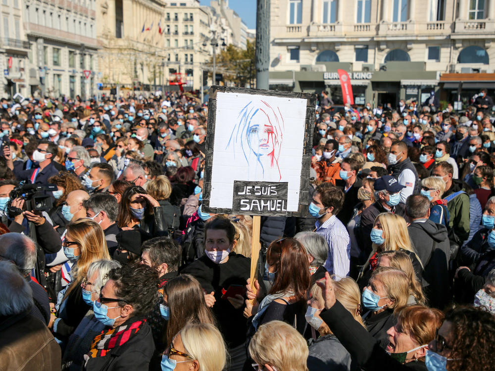 Demonstrators wearing face masks gather Sunday in Marseille, France, to pay tribute to teacher Samuel Paty, who was beheaded after he showed his class cartoons depicting the Prophet Muhammad.