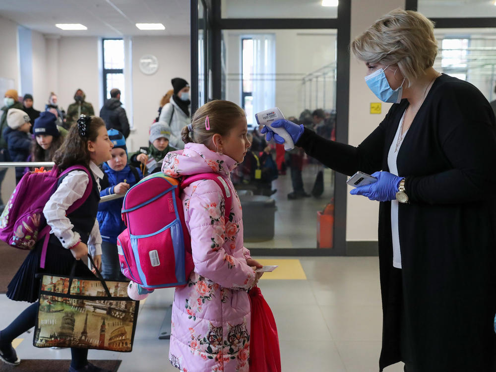 More than 40 million coronavirus infections have now been reported worldwide. Here, a staff member at a school in Moscow uses an infrared thermometer on Monday to screen students.