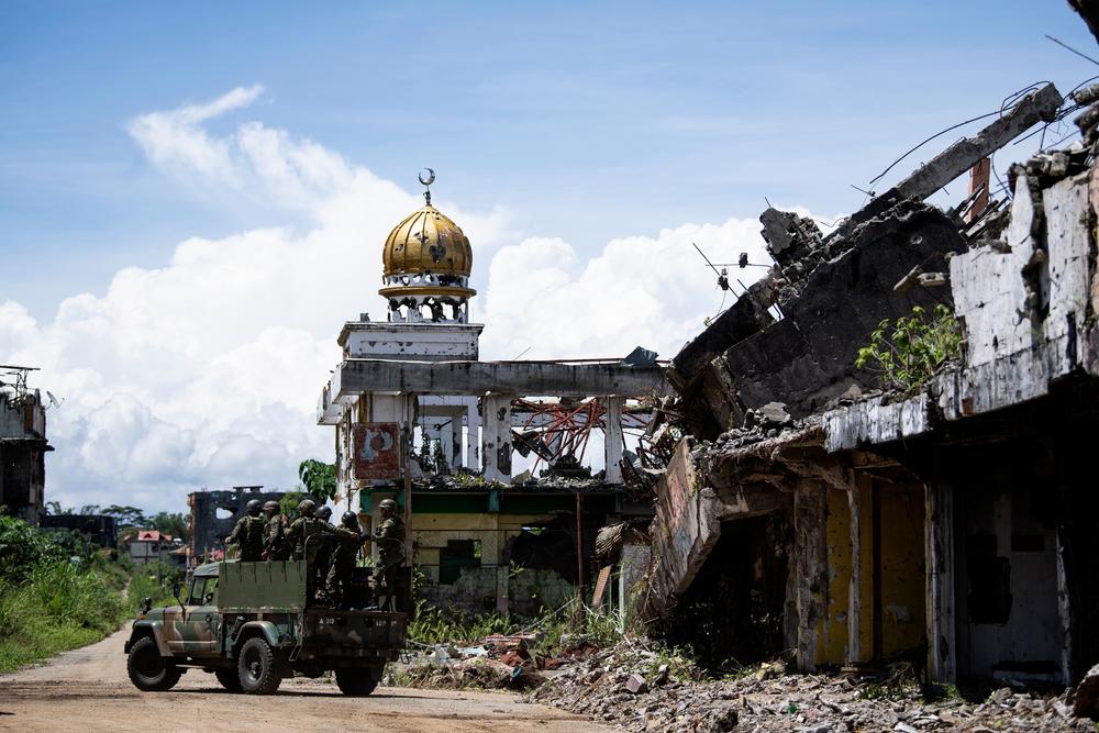 Soldiers on a military truck drive past destroyed buildings in Marawi last year.